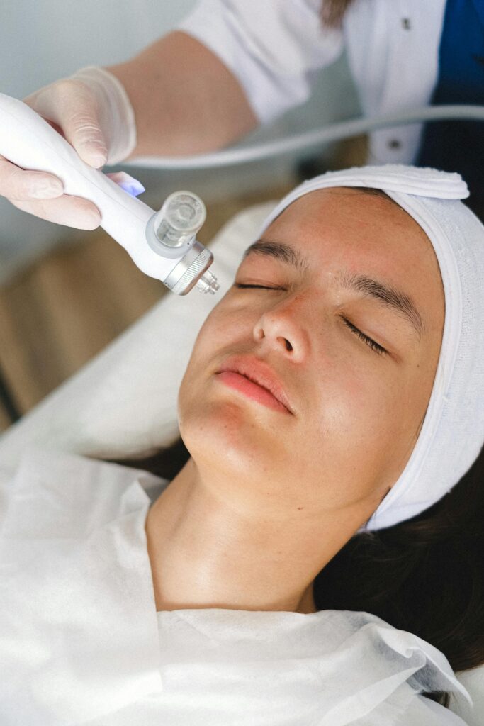 Licensed esthetician performing a medical-grade facial treatment using a professional skincare device on a client.