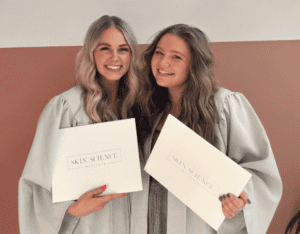 Two Skin Science Institute esthetician graduates holding diplomas at graduation ceremony in Utah