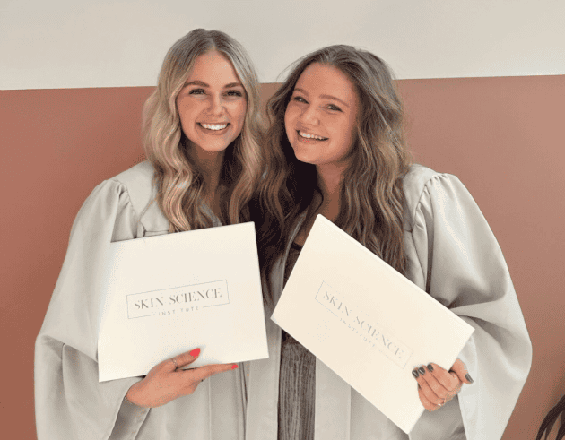 Two Skin Science Institute esthetician graduates holding diplomas at graduation ceremony in Utah